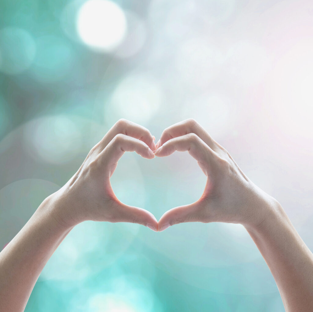 healthy human hand in heart shape showing love friendship on blurred abstract cool blue green sky color bokeh background: global eco environment csr natural resource awareness/ concept/ campaign/ idea