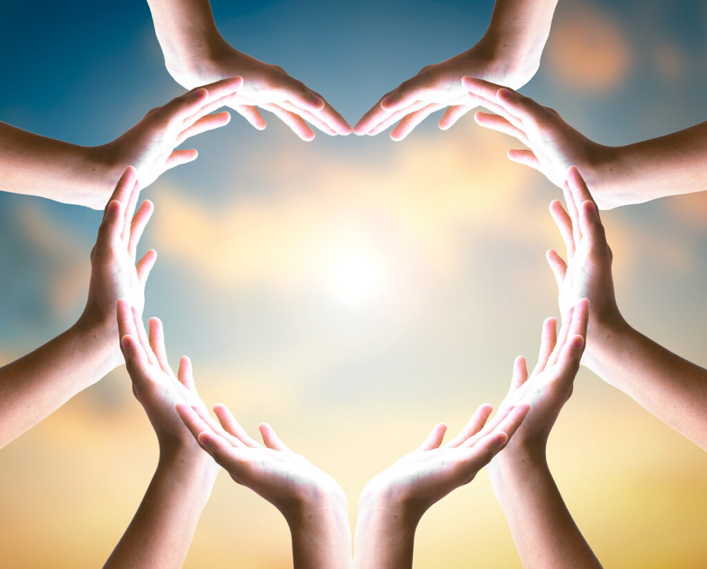 unity and diversity partnership as heart hands in sunset sky background