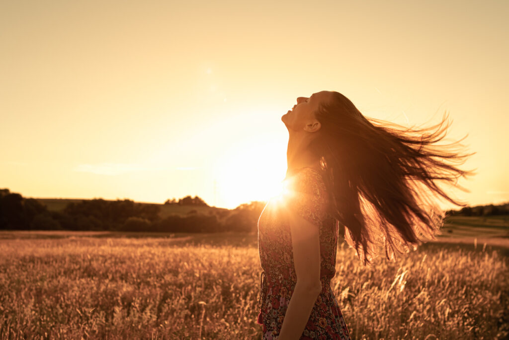 young woman looking up feeling happy in nature