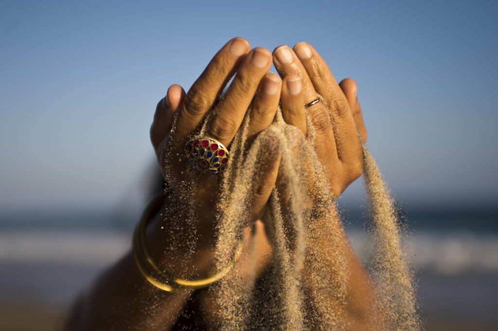woman's hands with golden sand falling